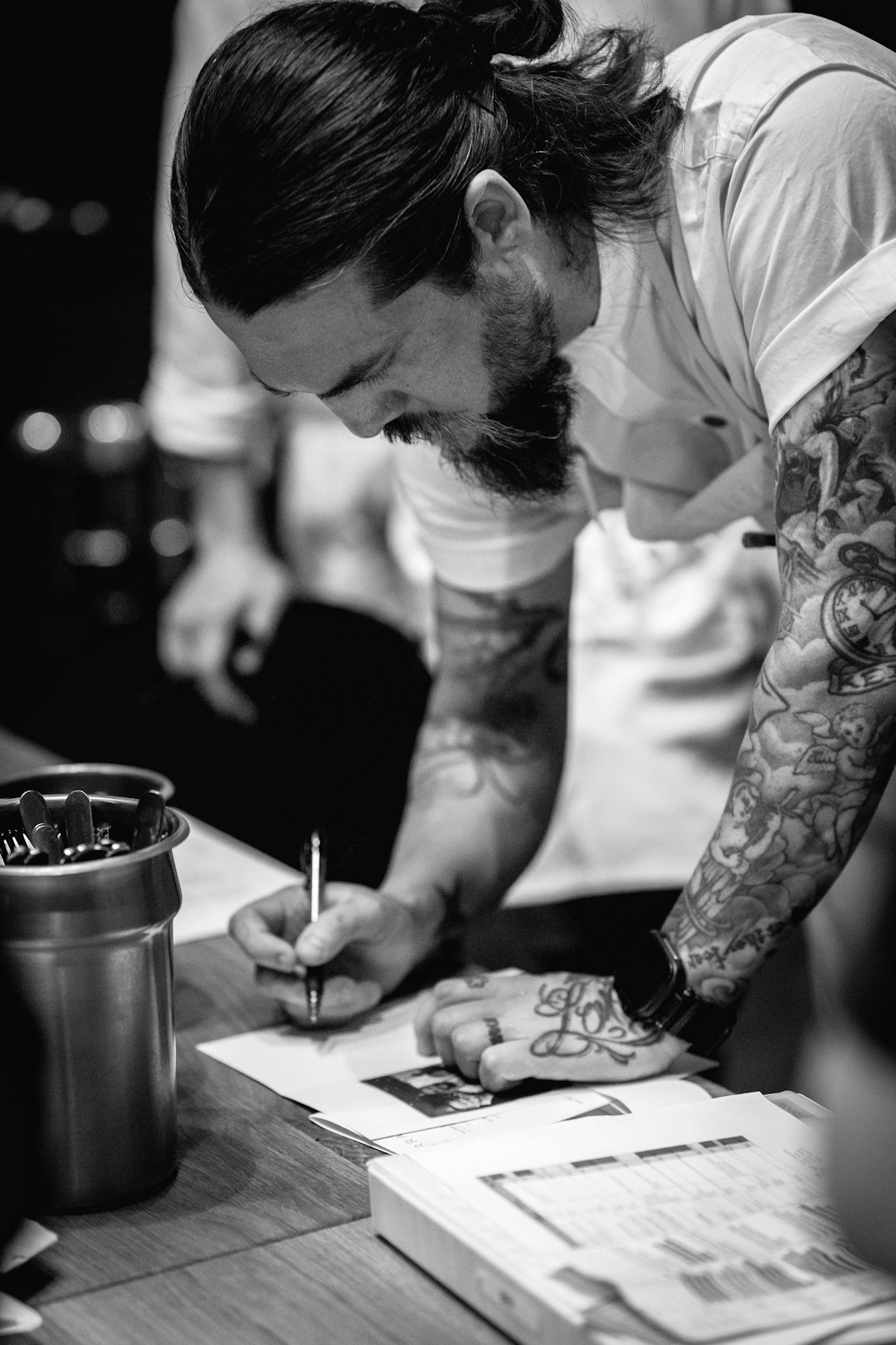 chef-with-tattoos-writing-on-paper-vrcruusabg